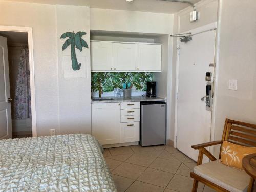 a kitchen with white cabinets and a bed in a room at Daytona Beach Hawaiian Inn in Daytona Beach