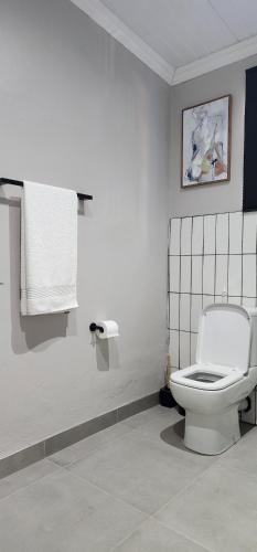 a bathroom with a white toilet and a towel at 72 on Circle in Bloemfontein