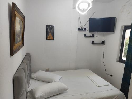 ein Zimmer mit einem Bett und einem Flachbildfernseher in der Unterkunft La Strada in Tirana