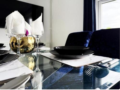 a glass table with plates and wine glasses on it at Modern Haven in Luton