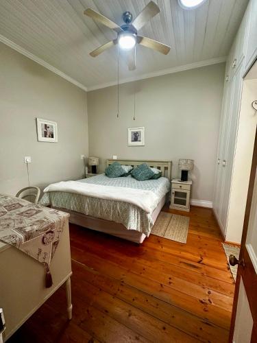 a bedroom with a bed and a ceiling fan at Corner Cottage on Hill in Mossel Bay