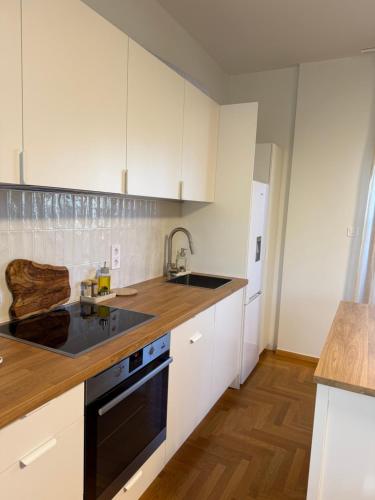 a kitchen with white cabinets and a black dishwasher at Quiet luxury studio next to airport in Paianía