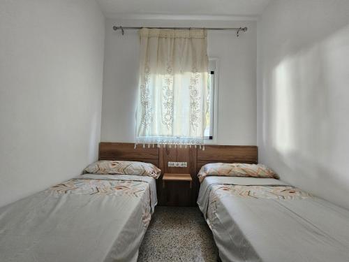 two beds in a small room with a window at Maison rurale à 800 m de plage in Restinga Smir