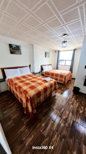 Dos camas en una habitación con suelo de madera. en Palacio de los Angeles, en San Felipe Hueyotlipan