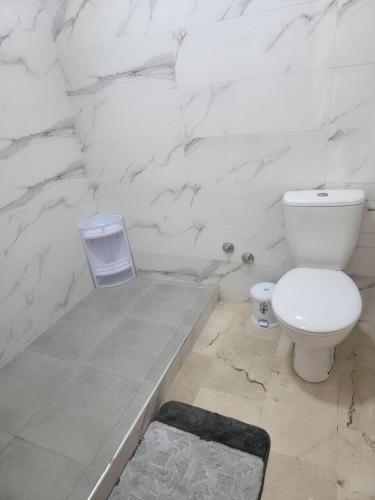 a white bathroom with a toilet and marble walls at Signature Villa à la Plage in Temara
