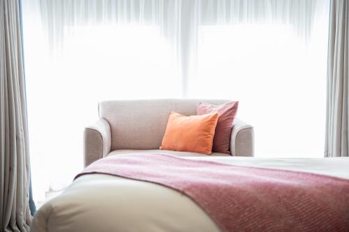 a bed with an orange pillow in front of a window at McGrorys in Culdaff