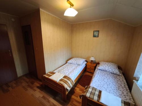 two beds in a small room with wooden floors at Noclegi pod Witowem in Niedźwiedź