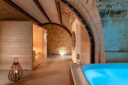 a bathroom with a tub and a stone wall at Elysium Boutique Apartment - Modica in Modica