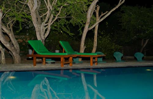 two green chairs next to a swimming pool at night at Yala Green Eco Lodge in Kirinda