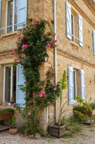 a building with pink flowers on the side of it at Aux roses de Cèdres in Salvagnac