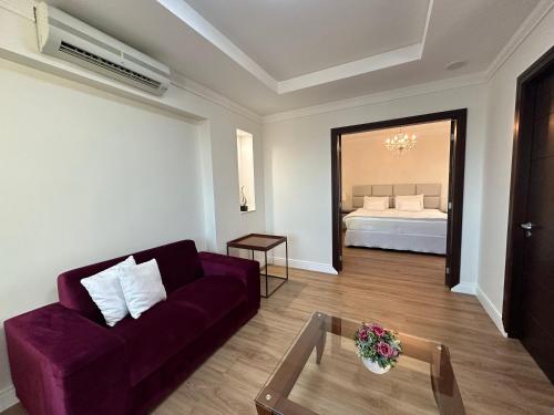 a living room with a purple couch and a bed at Villa Vergueiro Hotel in Passo Fundo