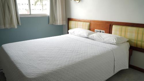 a bed with white sheets and pillows in a bedroom at Hotel Transcontinental in Ji-Paraná