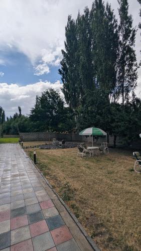 a park with benches and an umbrella on the grass at Soma Hotels Skardu in Skardu