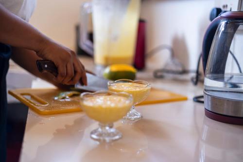 a person preparing two glasses of orange juice on a counter at Mem Luxury Apartments and Hotel in Paje