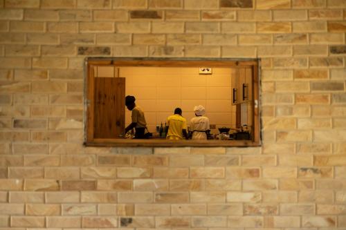 three people in a mirror on a brick wall at Mem Luxury Apartments and Hotel in Paje
