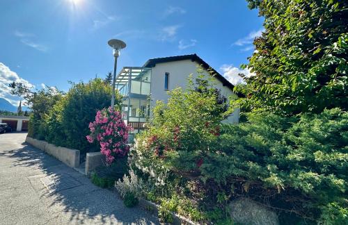 a white house with some bushes and flowers at Chasa Stefania, modernes Engadiner Haus mit Wellness und Sauna in Scuol