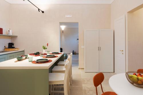 a kitchen with a large island with white cabinets and chairs at Elysium Boutique Apartment - Modica in Modica