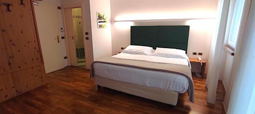 a bedroom with a large bed with a green headboard at Hotel Lilla' in Terlago