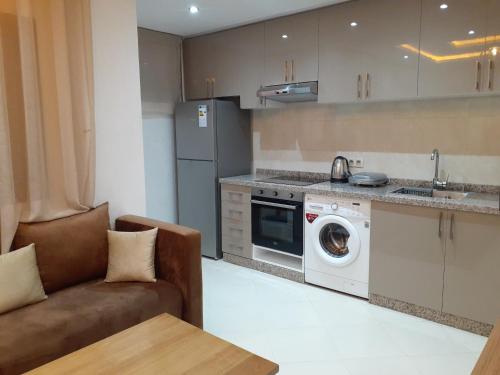a kitchen with a couch and a washing machine at Appartement cosy à 8 min de RAK à pied in Marrakech