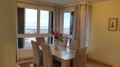 a dining room with a table and chairs and windows at Funchal Apartament Marina View with PARKING FREE in Funchal