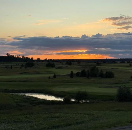 a sunset over a golf course with a pond at Lantligt läge nära golfbana in Västerås