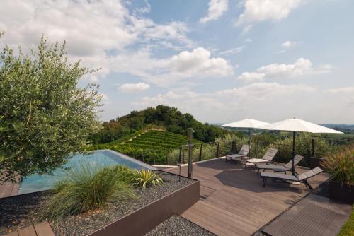 a patio with tables and chairs and a swimming pool at Col del Noc - Luxury Apartments & Pool Prosecco Hills in Cozzuolo