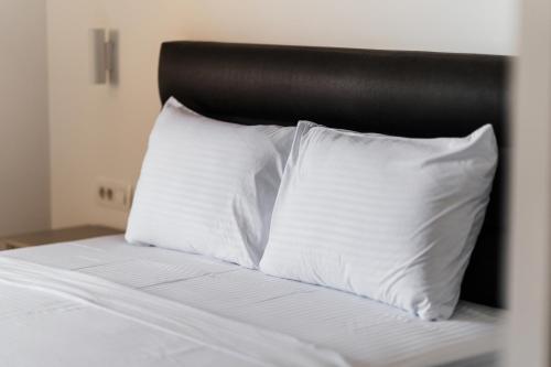a bed with white pillows and a black headboard at Vuelo Sobre by In Property in Becici
