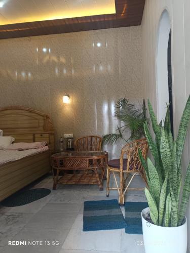リシケーシュにあるHappy Homeのベッドルーム1室(ベッド1台、テーブル、鉢植えの植物付)