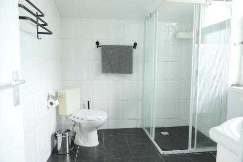 a white bathroom with a toilet and a shower at De Bosuil Drenthe in Spier