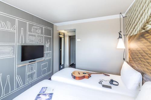 a bedroom with a guitar on a bed at Hotel ibis Lisboa Liberdade in Lisbon