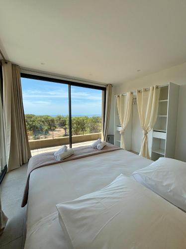 une chambre avec un grand lit avec une grande fenêtre dans l'établissement Casa Vitalba, à Zonza