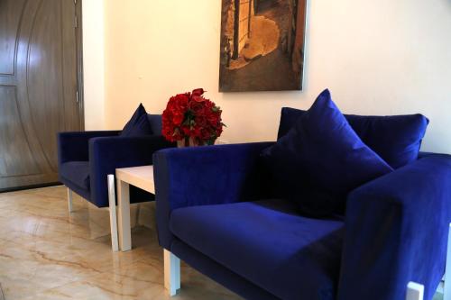 a living room with blue couches and a table with red flowers at Royal Suites Muscat in Ma‘ābīlah