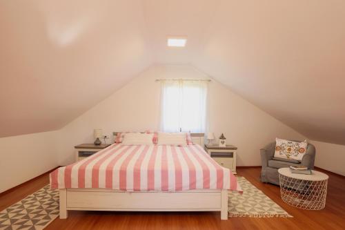 Un dormitorio con una cama y una silla y una ventana. en Vineyard house, en Tužno