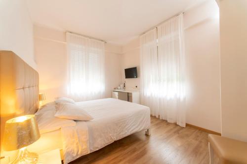 a white bedroom with a bed and a desk at Hotel Lilla' in Terlago