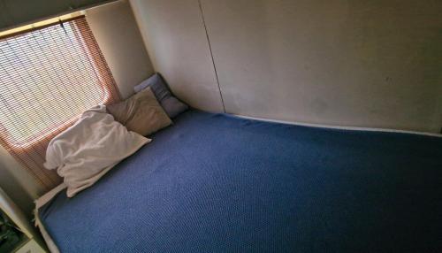 Cama pequeña en habitación pequeña con ventana en Camping Bakkum Caravan te huur, en Castricum