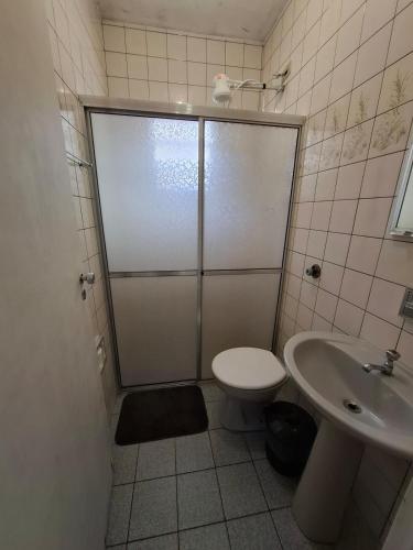 a bathroom with a shower and a toilet and a sink at Casa com churrasqueira e piscina in Itanhaém