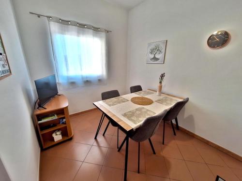 una sala da pranzo con tavolo, sedie e televisione di Apartment Pergola with Mediterranean Garden & BBQ a Portoroz