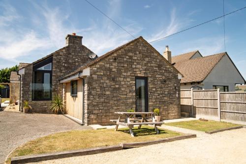 a brick house with a picnic table in front of it at The Captain's Retreat, Quiet 1 Bed Dog Friendly in Puncknowle
