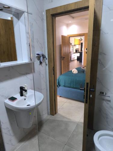 a bathroom with a sink and a toilet and a bed at Évasion Haut Standing à Saïdia in Saïdia