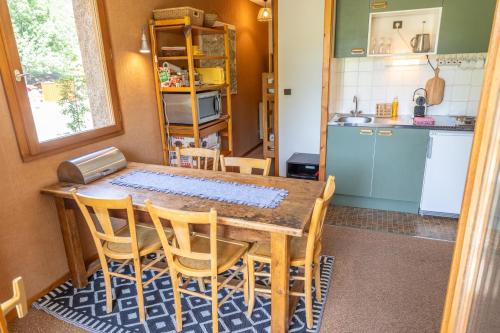 a kitchen with a wooden table and chairs and a kitchen with a counter at Bel appartement lumineux et confortable - Parc national des Écrins in Le Sarret