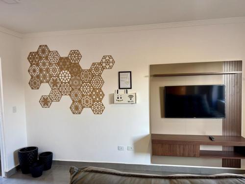 Una sala de estar con un televisor de pantalla plana en una pared. en Casa com piscina - Shangri-lá, en Pontal do Paraná