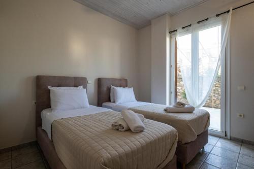 two beds in a room with a window at Mythos Suites-Dionysos apartment in Methoni