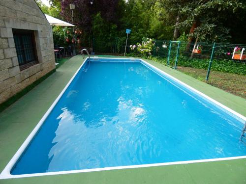 a swimming pool with blue water in a yard at Hotel Rural Camino Medulas in Ponferrada
