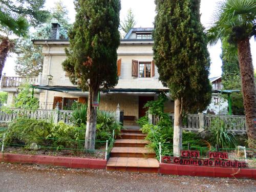 an old house with trees in front of it at Hotel Rural Camino Medulas in Ponferrada