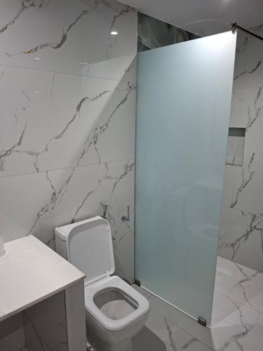 a bathroom with a white toilet and a marble wall at Vila Agushi in Ksamil