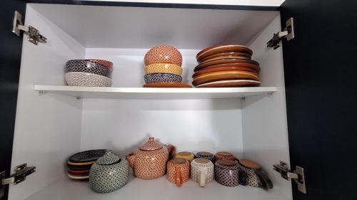 a shelf with vases and plates in a cabinet at Departamento 5 Min Centro Wifi Elevador in Pátzcuaro