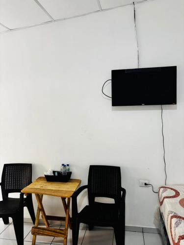 a room with two chairs and a table and a tv at LA CASONA SV Hostal in La Libertad