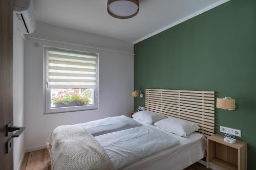a bedroom with a bed with a green wall at Balatonic Lime apartmanház in Siófok