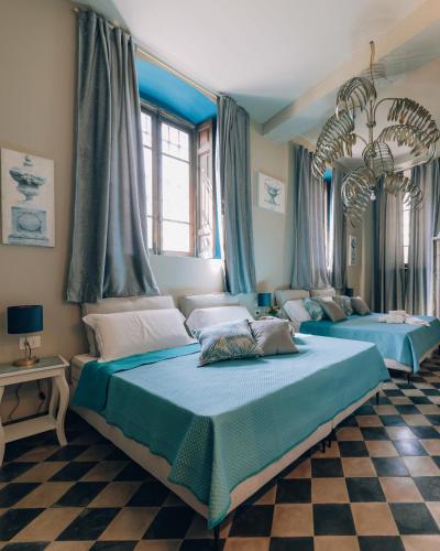 two beds in a bedroom with blue curtains at Palazzo Isabella residenza storica in Borgo San Giacomo in Borgo San Giacomo