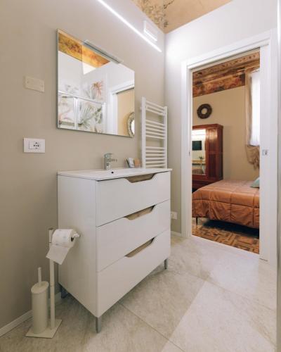 a white bathroom with a sink and a bedroom at Palazzo Isabella residenza storica in Borgo San Giacomo in Borgo San Giacomo
